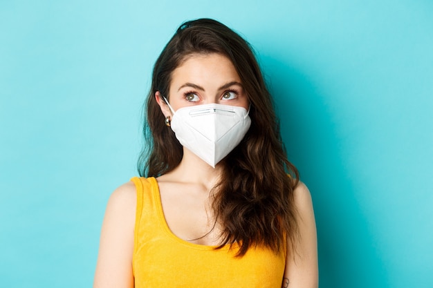 Covid coronavirus and social distancing close up portrait of young modern woman in respirator looking up