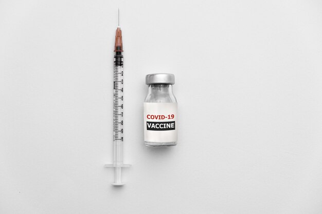 Covid coronavirus vaccine and syringe on white backgrounnd