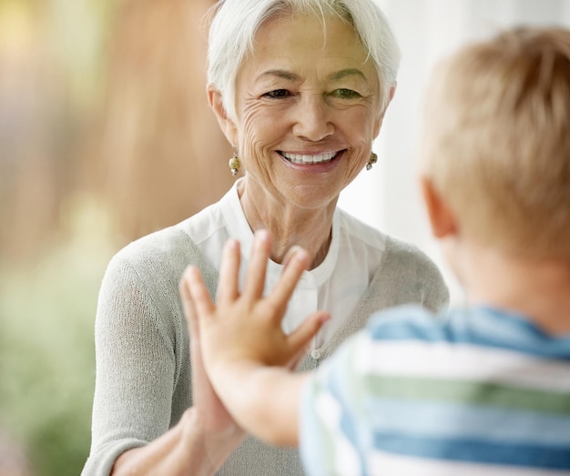 Covid-familie en raam met oma en jongen raken door barrière voor preventie en veiligheid tonen liefde, zorg en geluk Quarantaine coronavirus en isolatie met oudere vrouw en kind