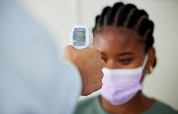 Covid-gezondheidszorg en vrouwelijke patiënt krijgen thermometercontrole bij een nalevingsfunctionaris tijdens overleg of afspraak Gezondheidshygiënevoorschriften en welzijn met een vrouw die een gezichtsmasker draagt