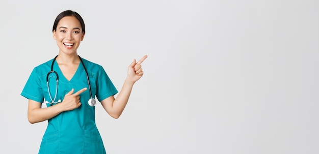 Концепция пандемии Covid медицинских работников улыбается веселой азиатской женщине-врачу в скрабе p ...