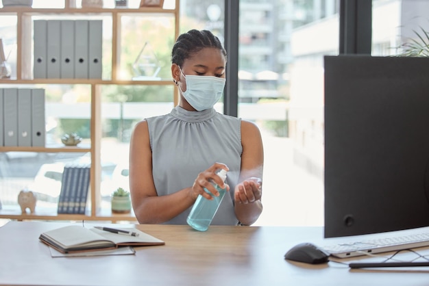 オフィスで働きながらビジネス黒人女性が掃除をしているcovidマスクと手指消毒剤