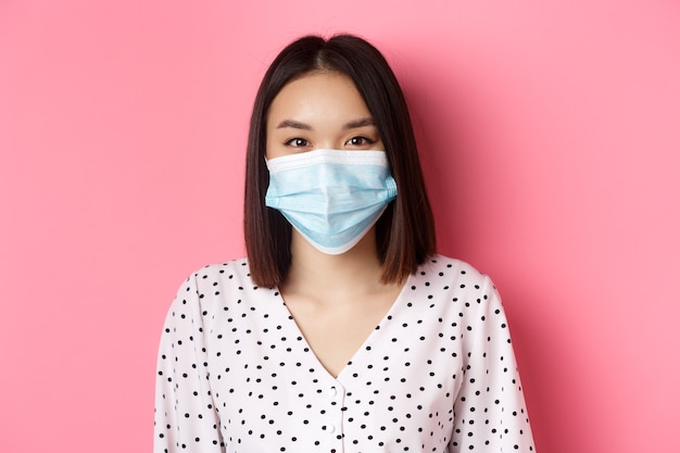 Covid pandemie en lifestyle concept close-up van mooie Aziatische vrouw in gezichtsmasker glimlachend met ogen...