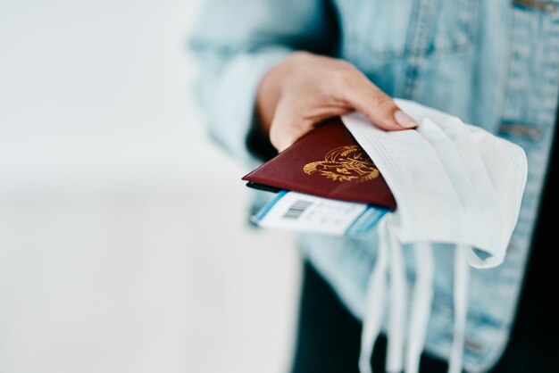 Foto covid persoon en handen met paspoort gezichtsmasker en bescherming voor instapkaart op luchthaven close-up reizen en toeristenreis van passagier met persoonlijk visum voor veiligheid of bescherming