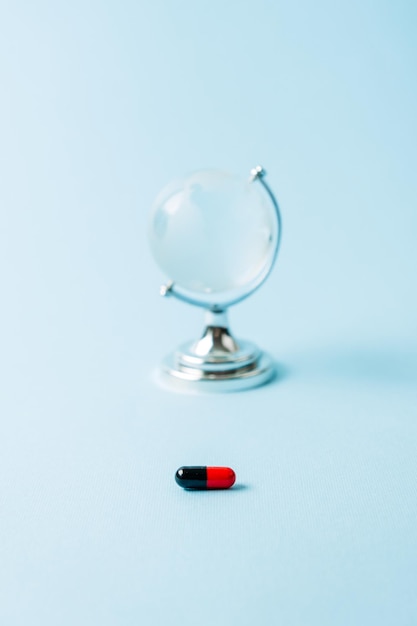 Covid pills concept one red and black capsule with glass globe covid coronavirus drugs first