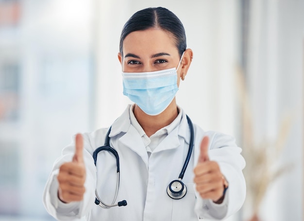 Covid portrait and thumbs up doctor with mask happy with hospital hygiene for infection safety Healthcare woman with hand gesture of success for virus prevention in consultation room