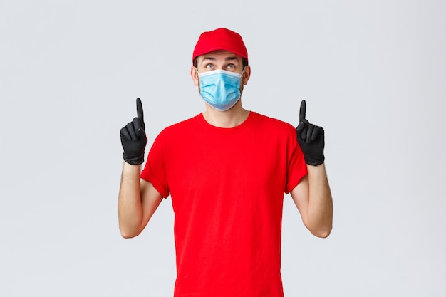 Covid selfquarantine online shopping and shipping concept smiling delivery guy red uniform cap and t...