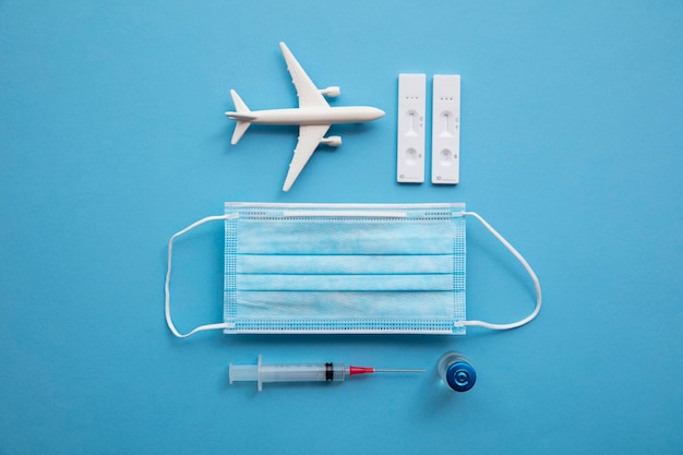 Covid vliegreis achtergrond vliegtuig met een coronavirus beschermend gezichtsmasker vaccin naald en test