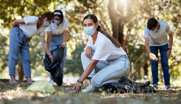 지역 사회 봉사를 하고 배경에 있는 사람들과 함께 환경을 청소하는 젊은 여성과 함께하는 Covid 자원 봉사자 및 자선 쓰레기를 줍는 친환경 환경 운동가의 초상화