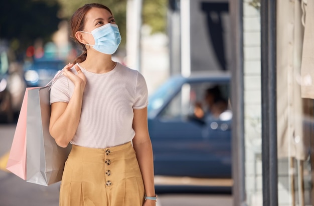 Covid winkelen stadsmode en vrouw met gezichtsmasker voor beveiliging tegen virus in de straat van winkelcentrum en met winkeltas Zieke meid klant met covid 19 die veilig is in de stad