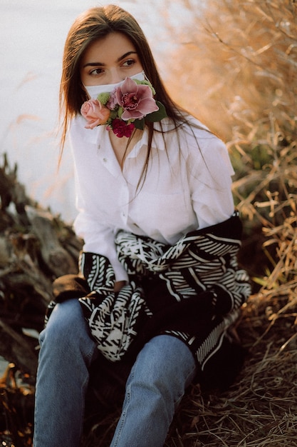 Foto covid19 bella ragazza in servizio fotografico con maschera floreale