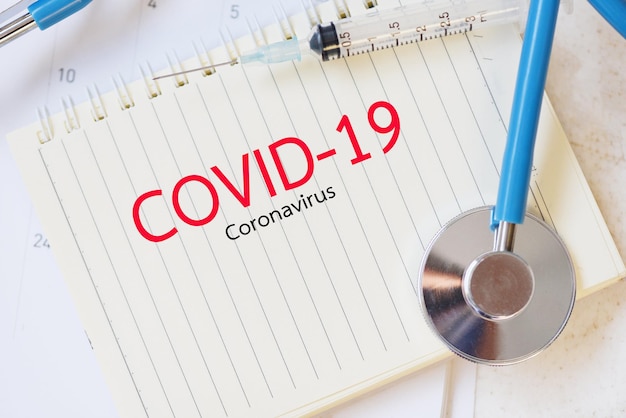 covid19 coronavirus concept with syringe injection medication drug and stethoscope on paper notebook coronavirus spread influenza medical crisis pandemic public health risk prevention