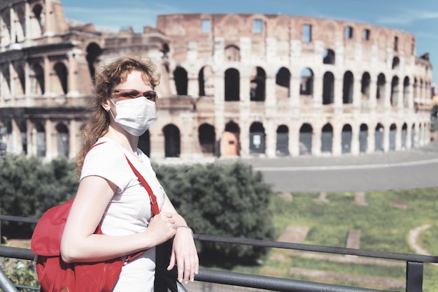 イタリアの COVID19 コロナウイルス ローマの空のコロッセオの横にある顔の医療マスクを着用した女性 コロナウイルスの発生により観光ランドマークが閉鎖されました