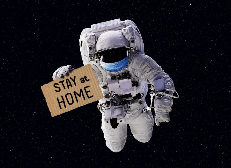 Photo covid19 coronavirus quarantine concept funny astronaut wearing medical mask in outer space with slogan stay at home on cardboard