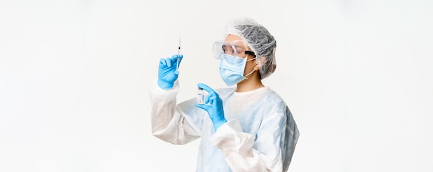 Covid19 coronavirus and vaccination campaign concept Asian female nurse or doctor in face mask filling syringe with vaccine standing over white background