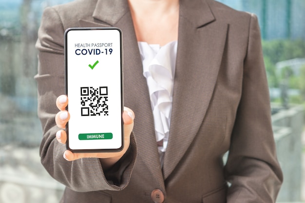 Covid19 gezondheidspas app-concept op slimme telefoon. Vrouw hodling telefoon. vrouw met slimme telefoon met een qr-code