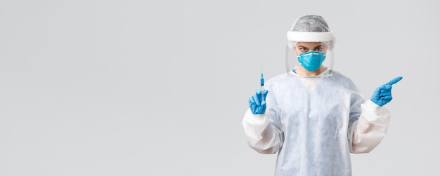 Covid19 medisch onderzoek diagnose gezondheidswerkers en quarantaine concept Ernstige arts in persoonlijk beschermend kostuum medische gasmasker wijzende linker greep spuit met vaccin