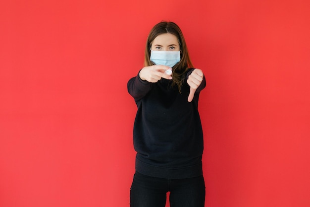Пандемия коронавируса COVID19 Молодая девушка на красном фоне защитная маска для лица держит шприц C