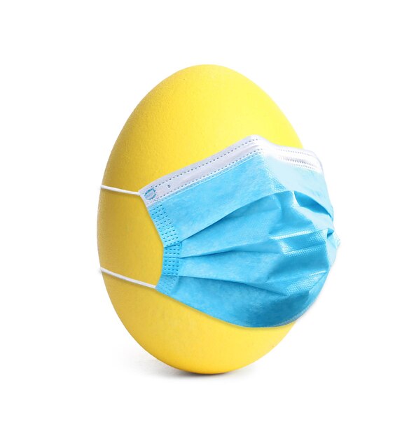 COVID19 pandemic Yellow Easter egg in protective mask on white background