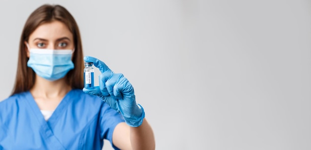 Covid19 preventing virus health healthcare workers and quarantine concept Closeup of seriouslooking young doctor or nurse in clinic lab showing coronavirus vaccine in ampoule