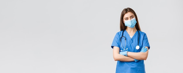 Covid19 preventing virus health healthcare workers and quarantine concept Determined female nurse or ER clinic doctor in blue scrubs personal protective equipment cross arms confident