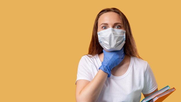 COVID19-symptoom Ziekterisico Bang geïnfecteerde vrouwelijke student in beschermende gezichtsmaskerhandschoenen die lijden aan keelpijnpijn geïsoleerd op beige kopieerruimte Coronavirus-uitbraak Veilig onderwijs