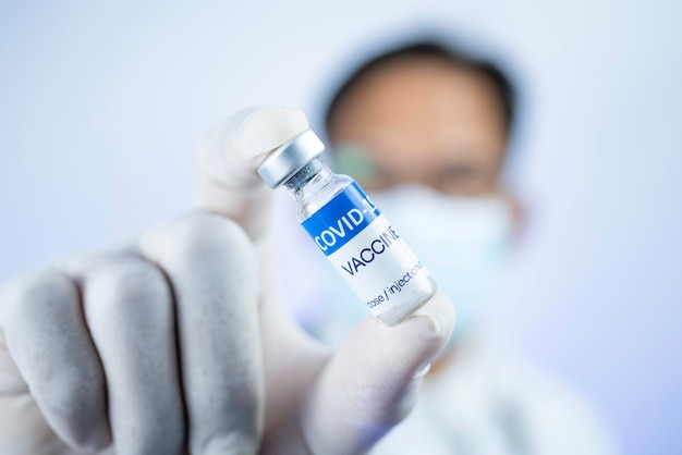 Концепция вакцины COVID19 Врач со стетоскопом на плече держит вакцину COVID19