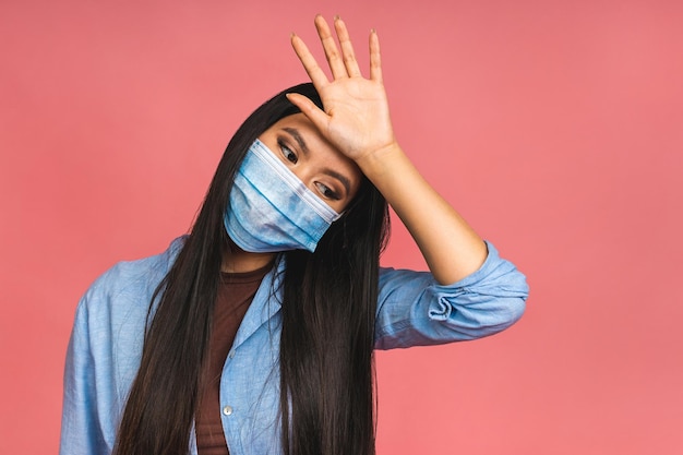 Covid19 virus health and medicine concept Portrait of young asian woman wearing medical protective mask during coronavirus quarantine isolated over pink background