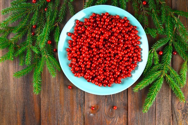 Cowberry, foxberry, cranberry, lingonberry on a blue ceramic dish on a brown wooden table.