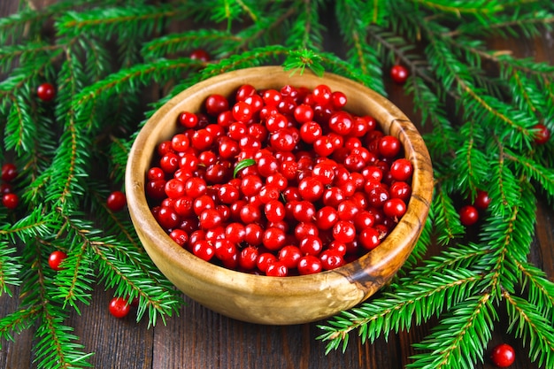 Cowberry, foxberry, cranberry, lingonberry in a wooden bowl on a brown wooden table.