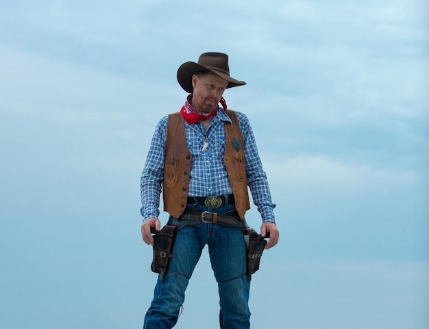 Cowboy in black suit and cowboy hat man with west vintage pistol revolver gun and marshal ammunition