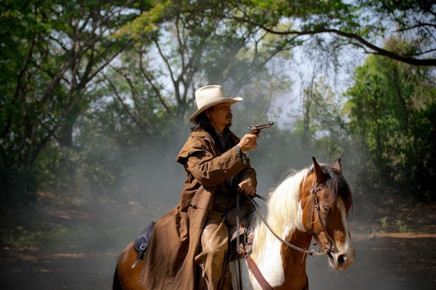 cowboy riding horse and holding gun in his hand are ready for shooting