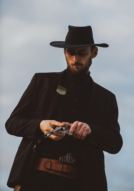 Cowboy shooter in black suit and cowboy hat Serious man with wild west guns retro pistol revolver an