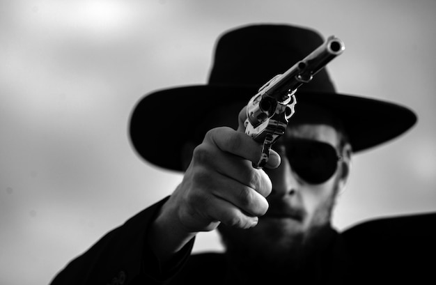 Фото Ковбой-стрелок в черном костюме и ковбойской шляпе серьезный человек с оружием дикого запада ретро пистолет револьвер