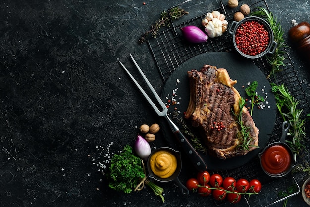 Cowboy steak met kruiden op een stenen achtergrond eersteklas rib op het bot bovenaanzicht Op een zwarte stenen achtergrond