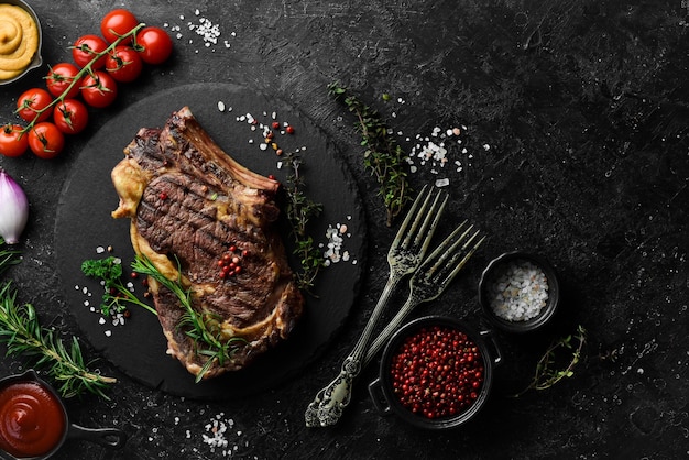 Cowboy steak with spices on a stone background firstclass rib on the bone top view On a black stone background