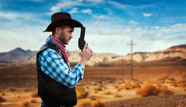 Cowboy with revolver prepares to gunfight in gesert valley, western. Vintage male person with gun, wild west lifestyle