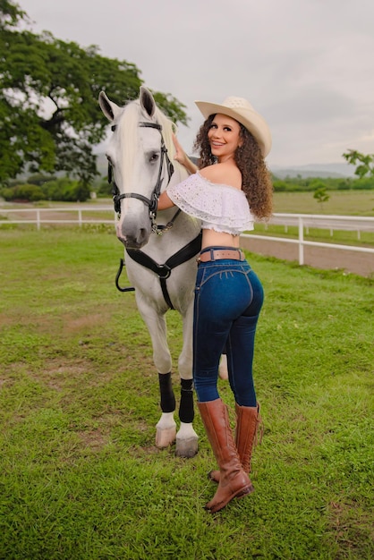 フィールドで彼女の美しい白い馬の横にある騎乗位