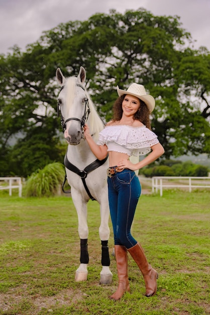 フィールドで彼女の美しい白い馬の横にある騎乗位