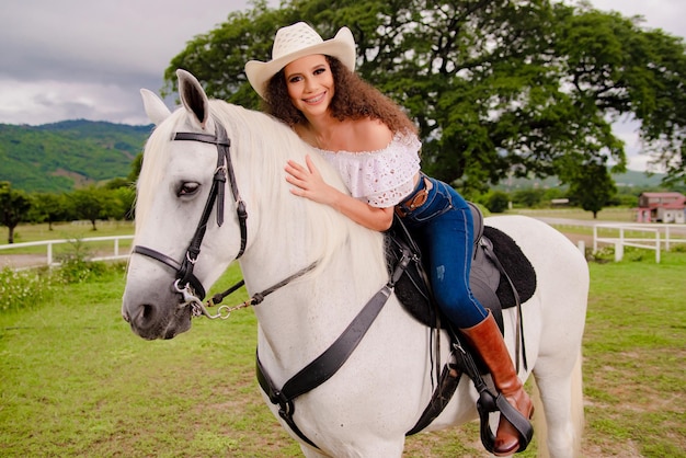 フィールドで彼女の美しい白い馬の横にある騎乗位