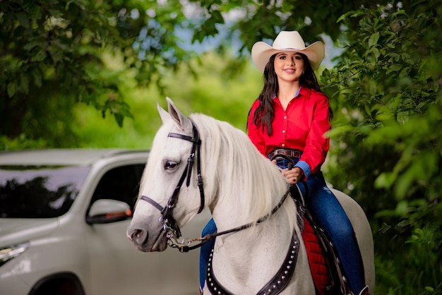 cowgirl riding next to her horse in a green forest