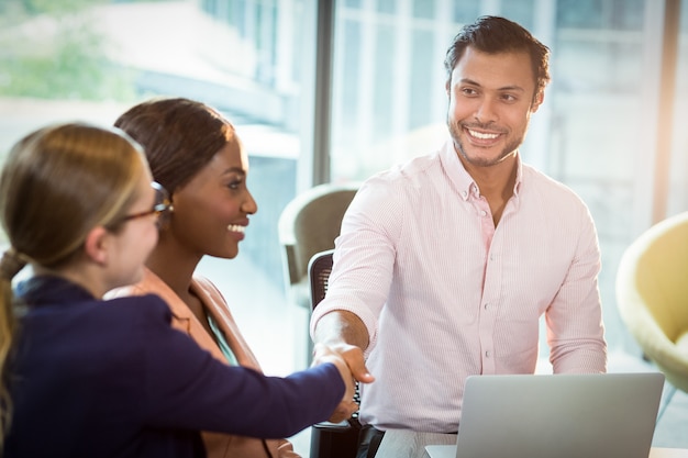 Coworker shaking hands with a colleague during meeting