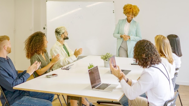 Photo coworkers applauding an african woman after a presentation