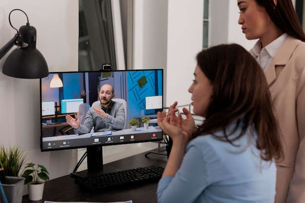 Foto i colleghi discutono della strategia con il partner commerciale in videochiamata, parlando della strategia del progetto di avvio. dipendenti che chattano con il cliente in videoconferenza nell'ufficio di coworking