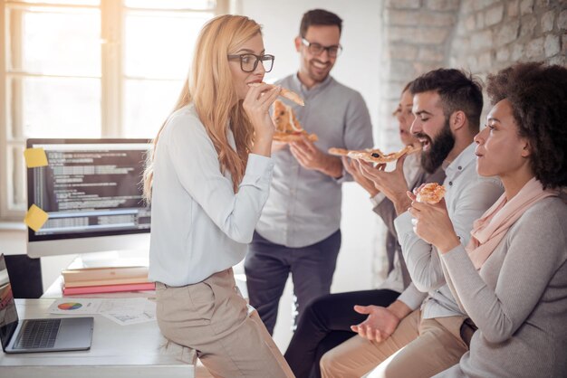 Coworkers eating pizza during break in office