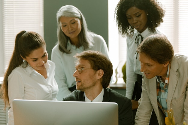 Coworkers gathered together in front of computer monitor