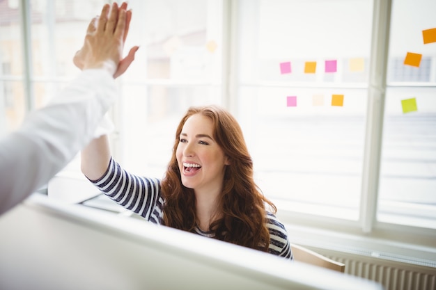 Coworkers giving high-five in creative office