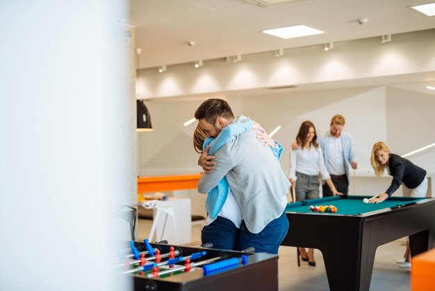 Coworkers playing a foosball table in an office.