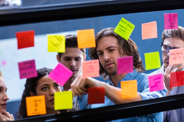 coworkers reading a post it on a window