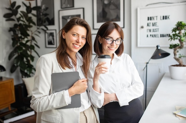 Coworking concept portret van gelukkige twee vrouwelijke ondernemers poseren en lachend naar de camera in cosy